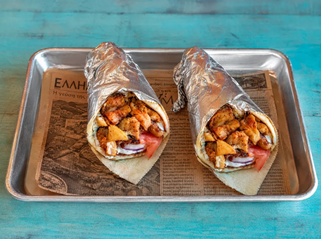 Two chicken gyros in pita on a tray